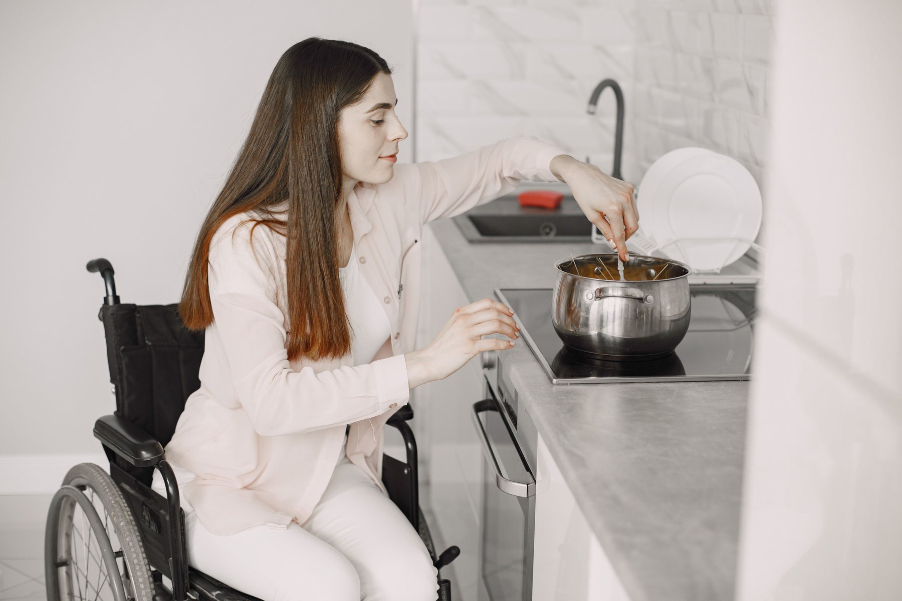 Woman using a wheelchair cooking independently in a bright, modern accessible kitchen