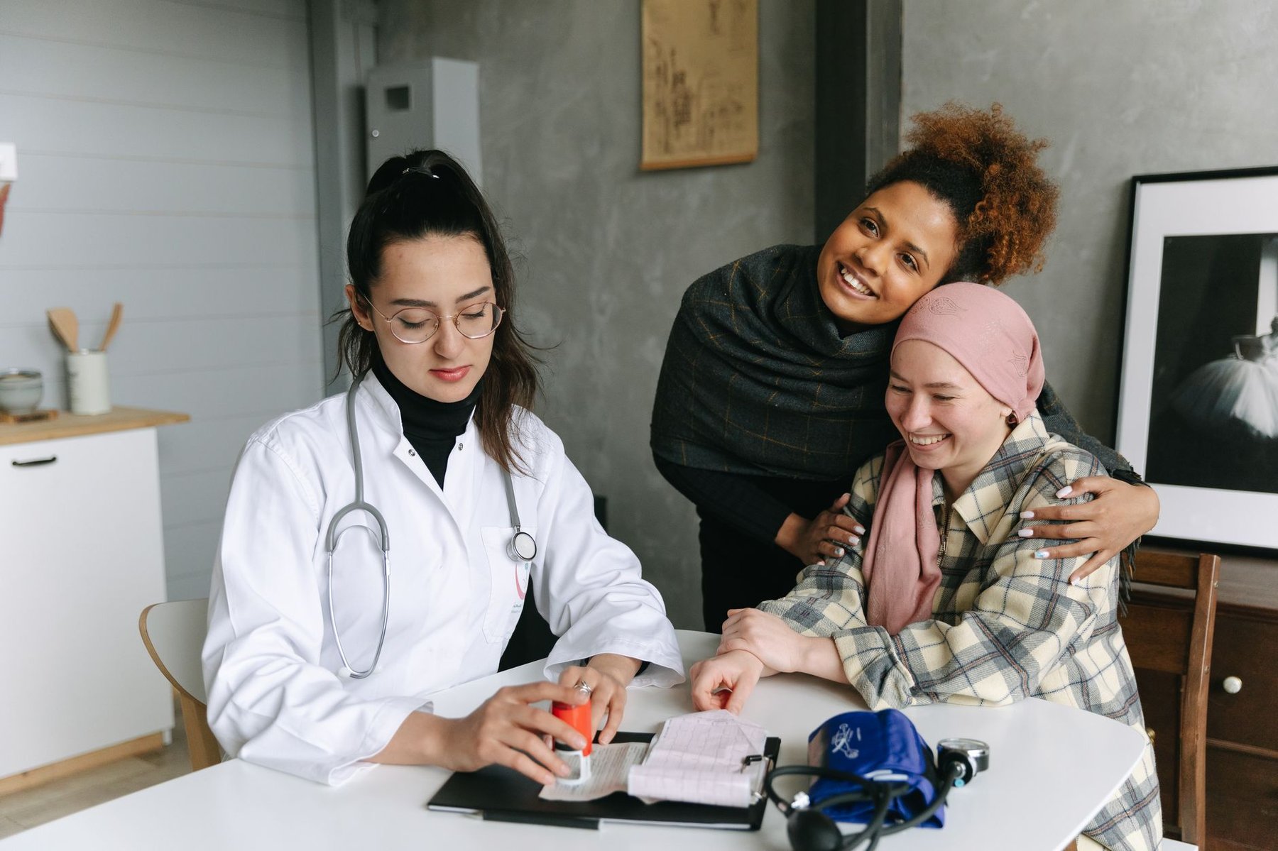 Doctor going through a patient's health records with a woman managing a complex condition and her support person at a clinic desk