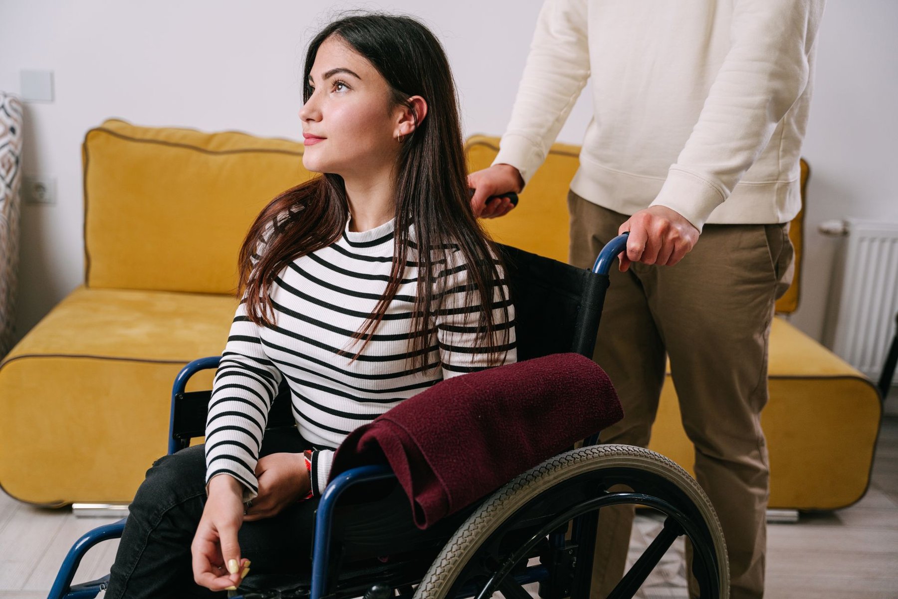 Support worker assisting a young woman in a wheelchair in a bright, comfortable indoor setting