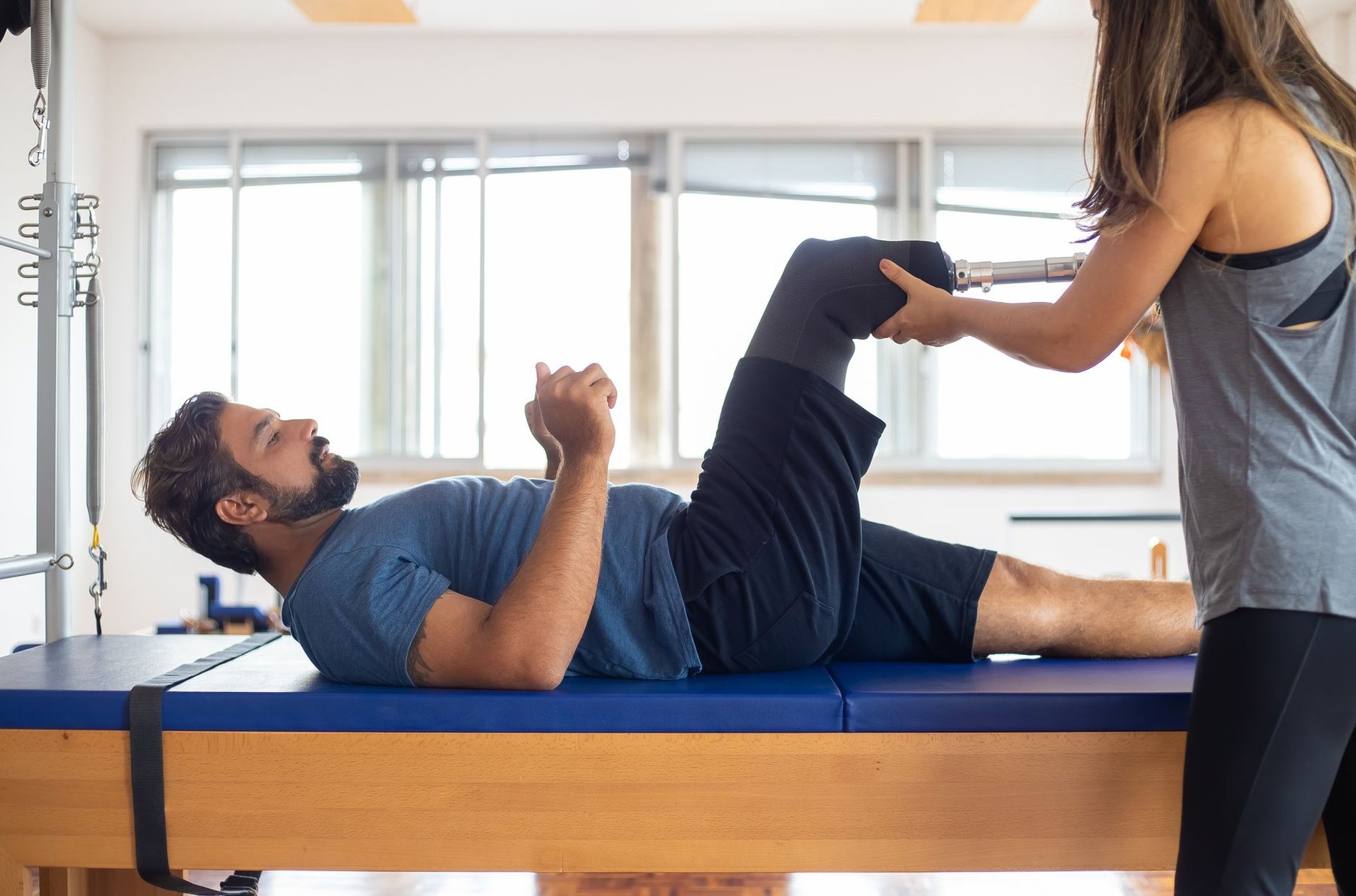 Physiotherapist supporting a man with a prosthetic leg during a rehabilitation session after amputation