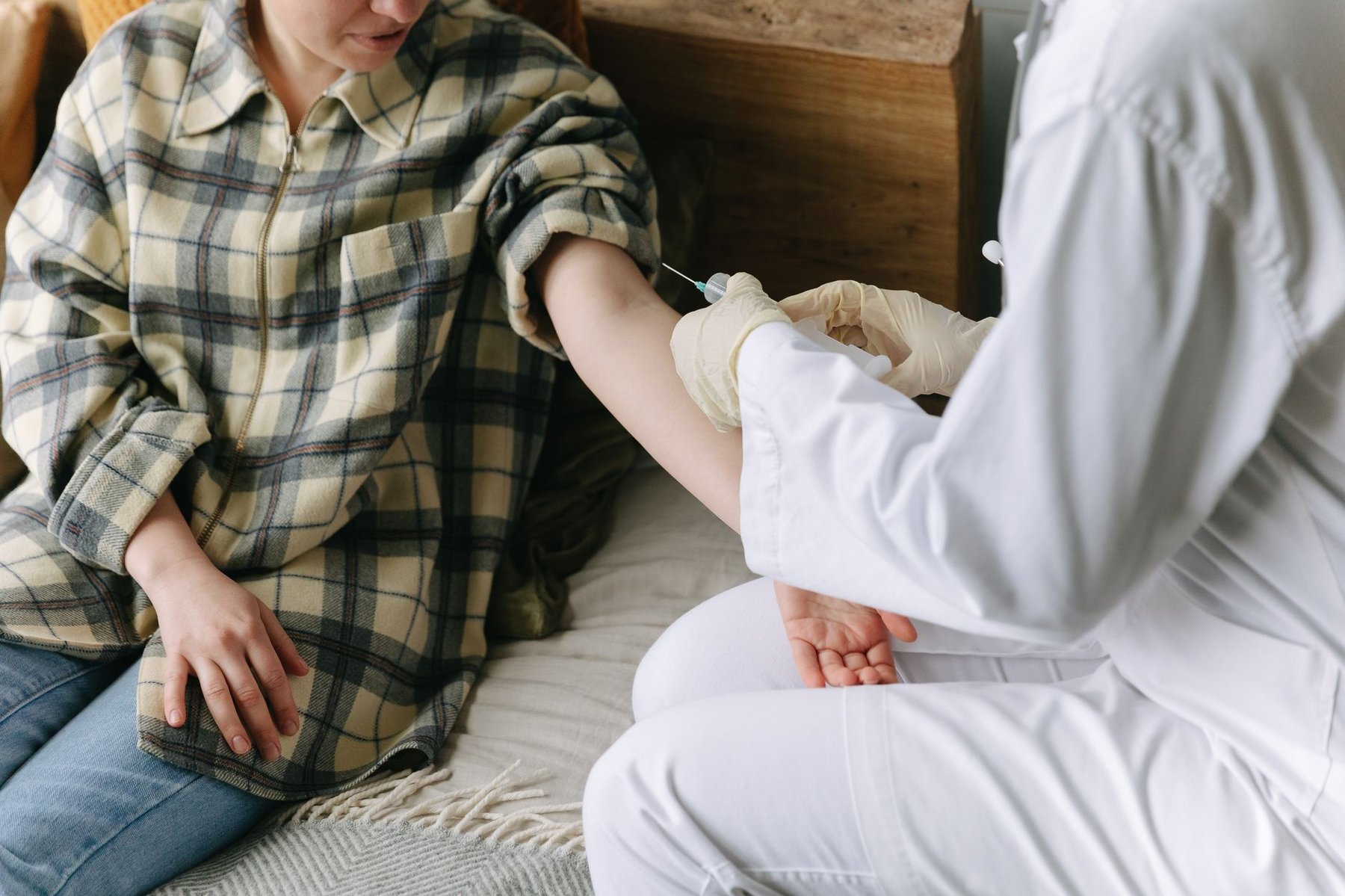 A support worker administering a subcutaneous injection to a client at home, reflecting compassionate in-home care