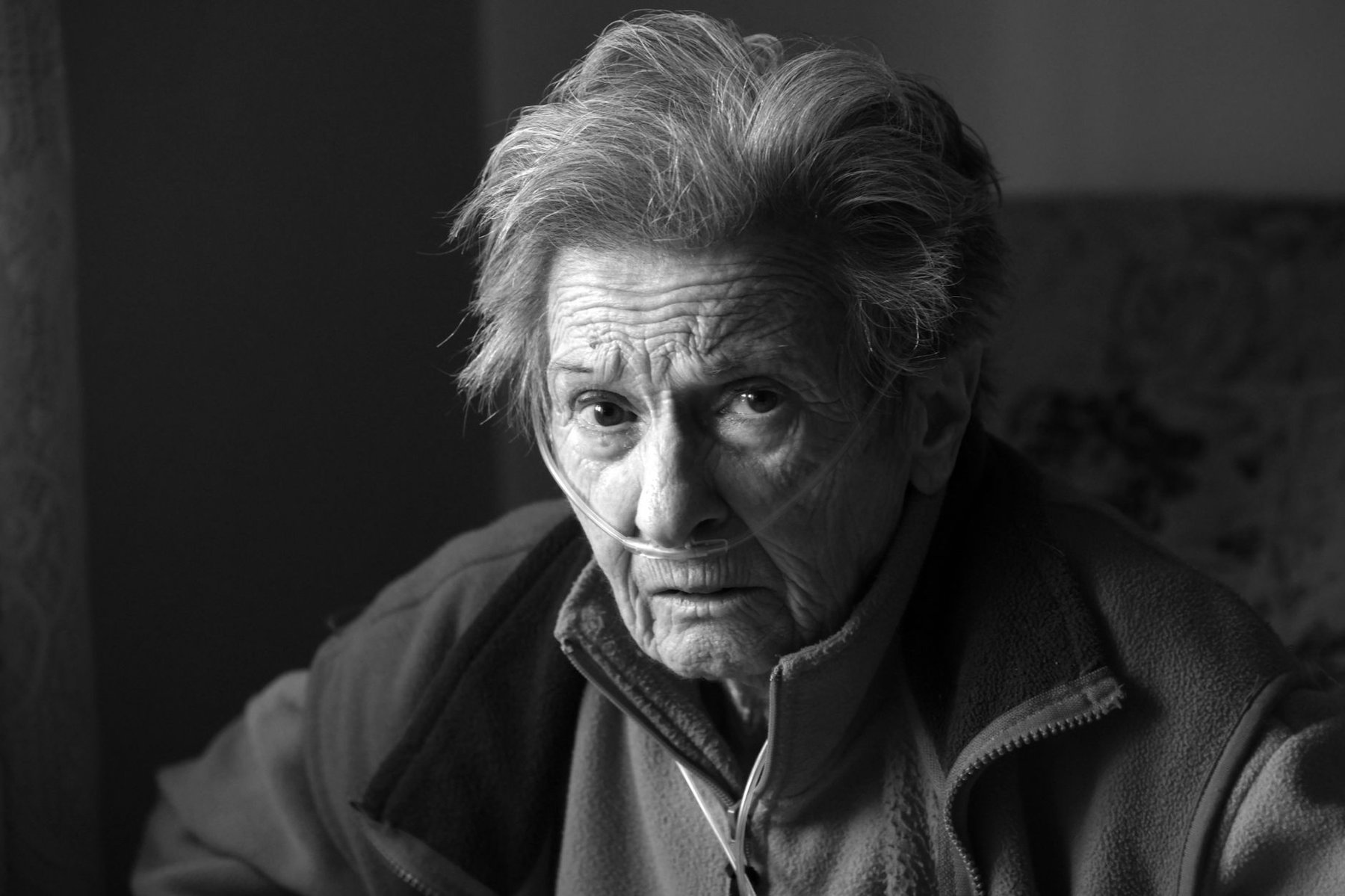 Elderly person receiving oxygen support at home, portrayed in an intimate black-and-white portrait conveying resilience during home respiratory care